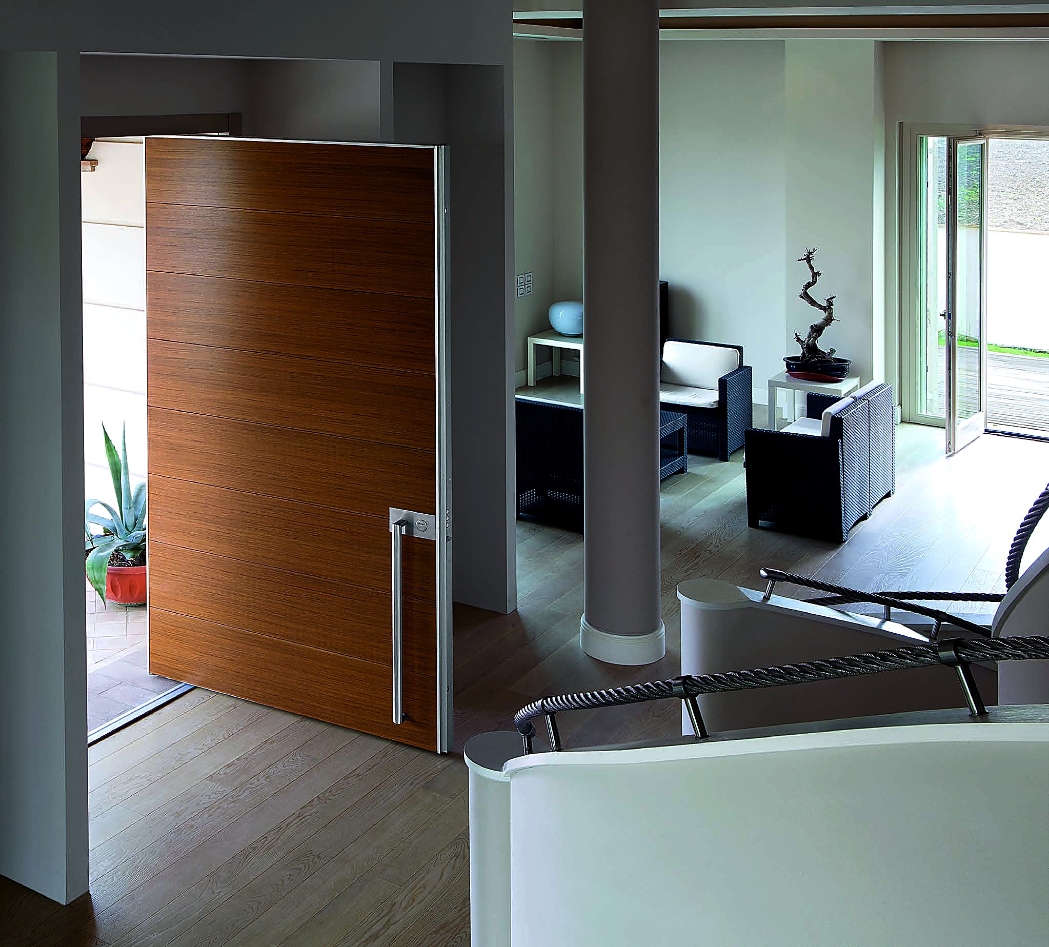 AURUM pivot door in horizontal teak, open mid-pivot inside a modern residence, full-height steel bar handle